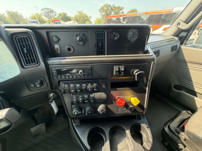 Interior dash of a 2023 International LT625 conventional sleeper showing control panel with switches, vents, gauge cluster, and cup holders.