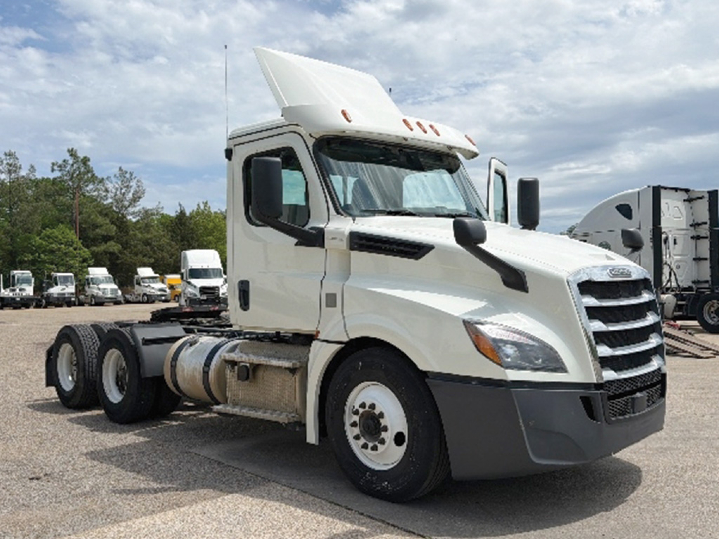 Truck cab showcases Freightliner Cascadia 126 daycab with white paint and extended hood, front grille, dual rear axles, daycab configuration.