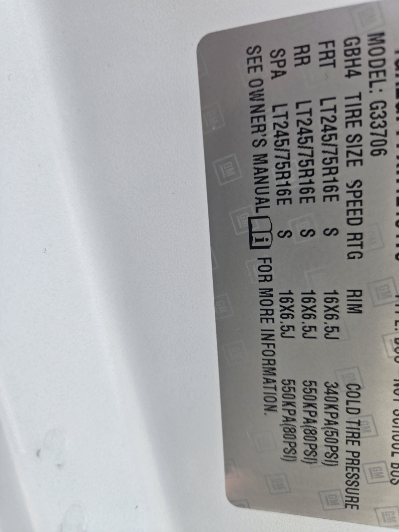 GM van label with tire and axle specs visible in vehicle door jamb; includes model, GVWR, front/rear tire sizes, speed rating, and cold tire pressure details.