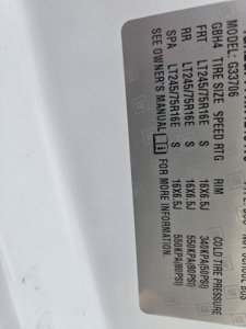 GM van label with tire and axle specs visible in vehicle door jamb; includes model, GVWR, front/rear tire sizes, speed rating, and cold tire pressure details.
