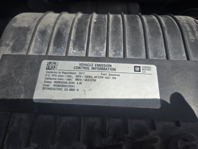 Vehicle Emission Control Information label on Chevrolet Express 3500 engine bay cover showing GM logo and regulatory details.