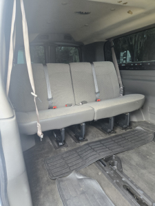 Chevrolet Express 3500 rear interior showing 3-row bench seat with grey upholstery and seatbelts, vinyl floor mats, and a cargo area. 