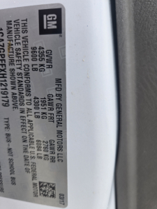 GM badge plate showing GVWR 9355 LB (4255 kg), GAWR front 4950 LB (2239 kg), GAWR rear 7000 LB (3175 kg); vehicle safety standard statement and VIN partial; General Motors LLC by GM.
