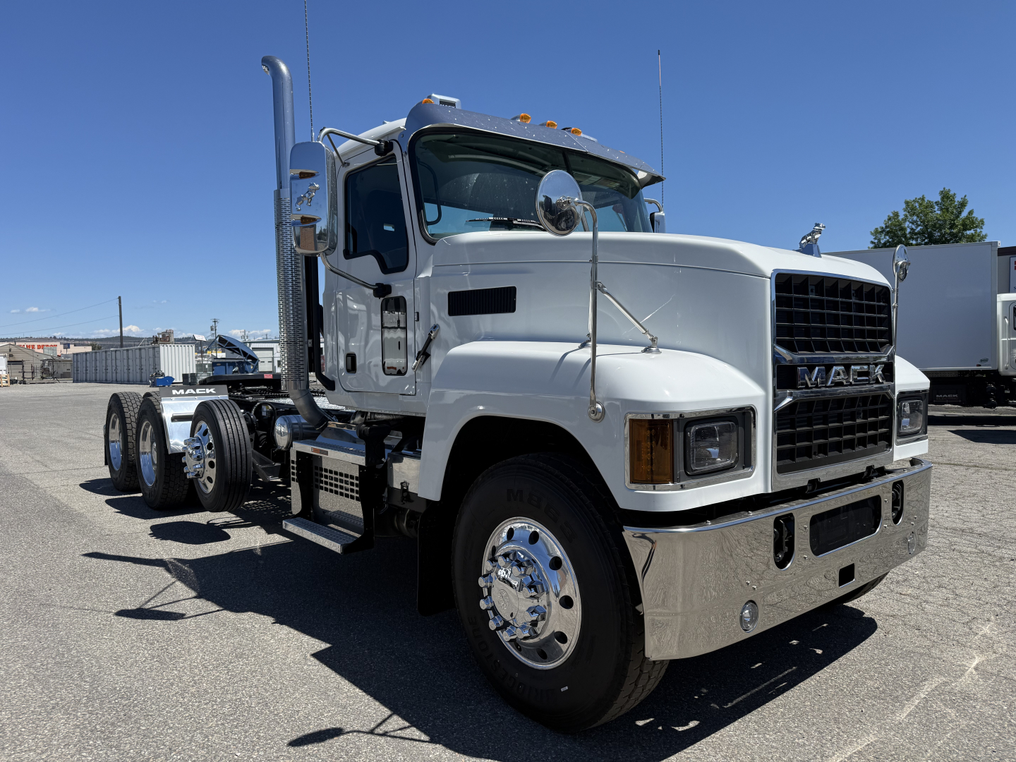 Mack PI84T conventional daycab truck in white, front three-quarter view with chrome bumper and dual rear axles, showing grille and side mirrors.