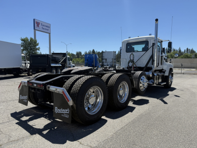 Mack PI84T tractor-trailer chassis rear view showing triple rear axles and dual-rear tires with mudflaps.