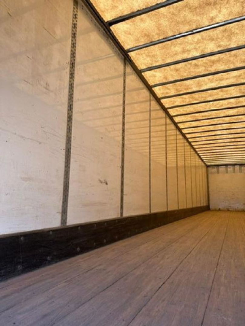 Interior of a long trailer van showing empty cargo space with wood floor and sidewalls.