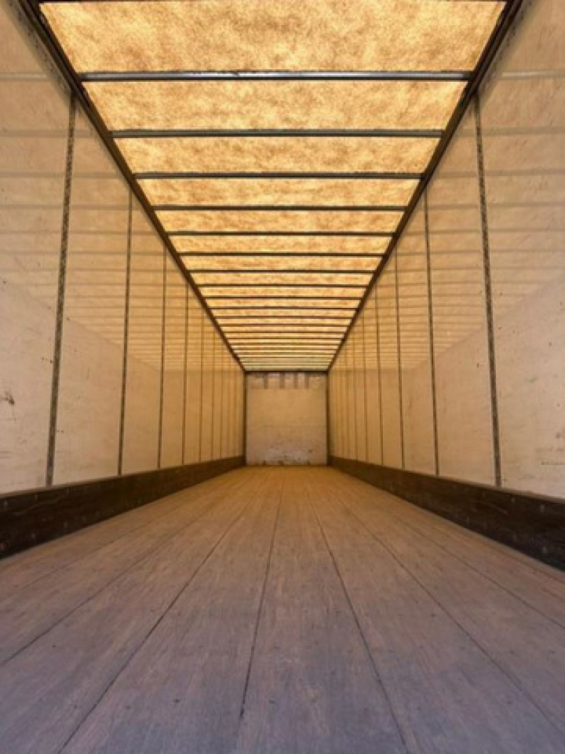 Trailer interior long cargo area with wooden floor and light panels along top, side walls plain