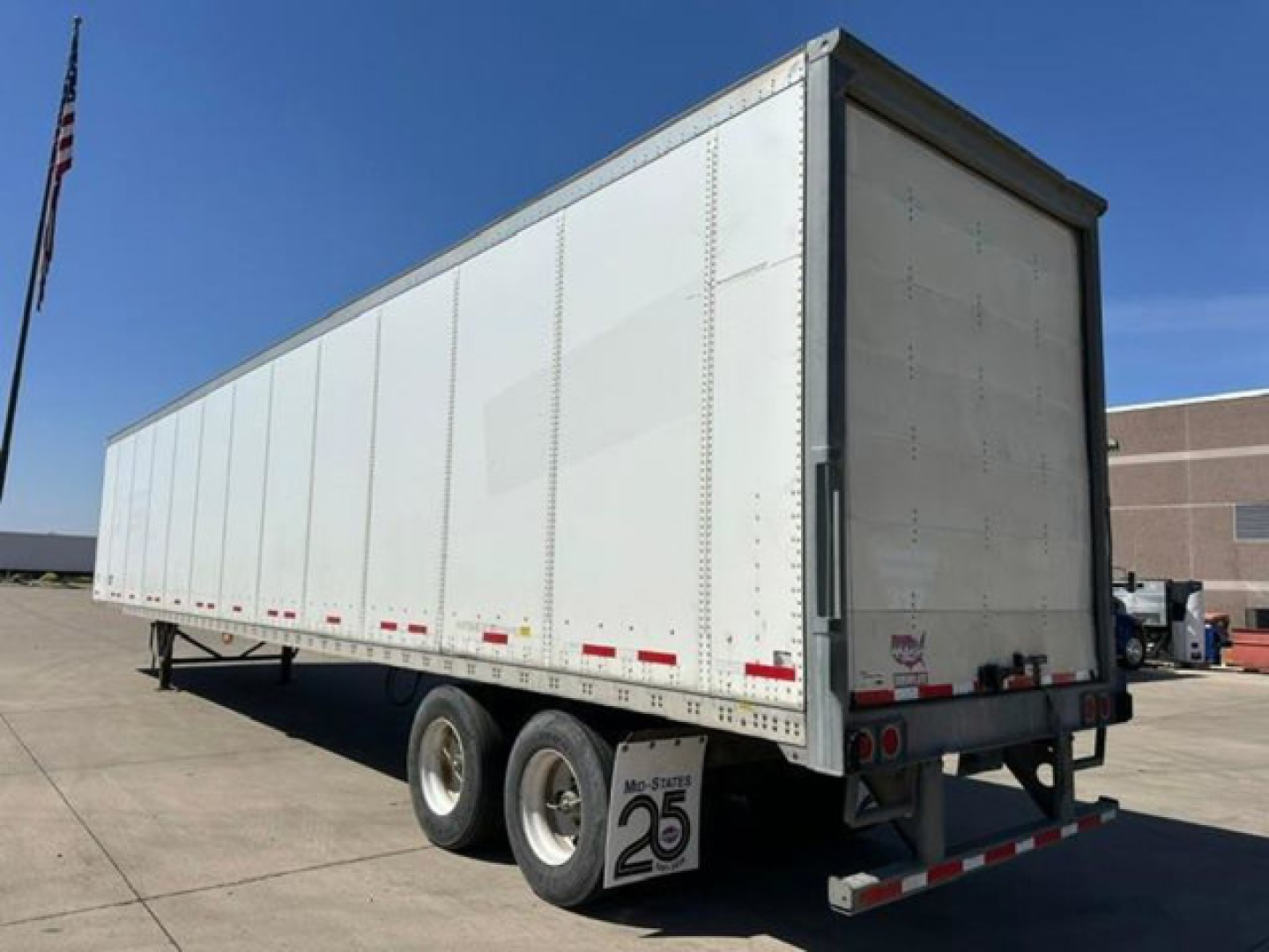 Trailer side and rear view showing a white 2016 Wabash van trailer with dual rear axles, tandem wheels, and rear doors; VIN 1JJV532D6GL908655 and stock U90923 visible.