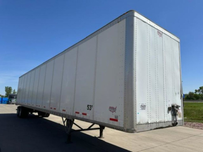 Trailer front left view of a 53' white Wabash van trailer in a parking lot showing side panels and front corner with landing gear.