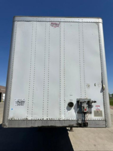 Rear view of a white Wabash van trailer with riveted aluminum panels and a service coupling at the lower right side.