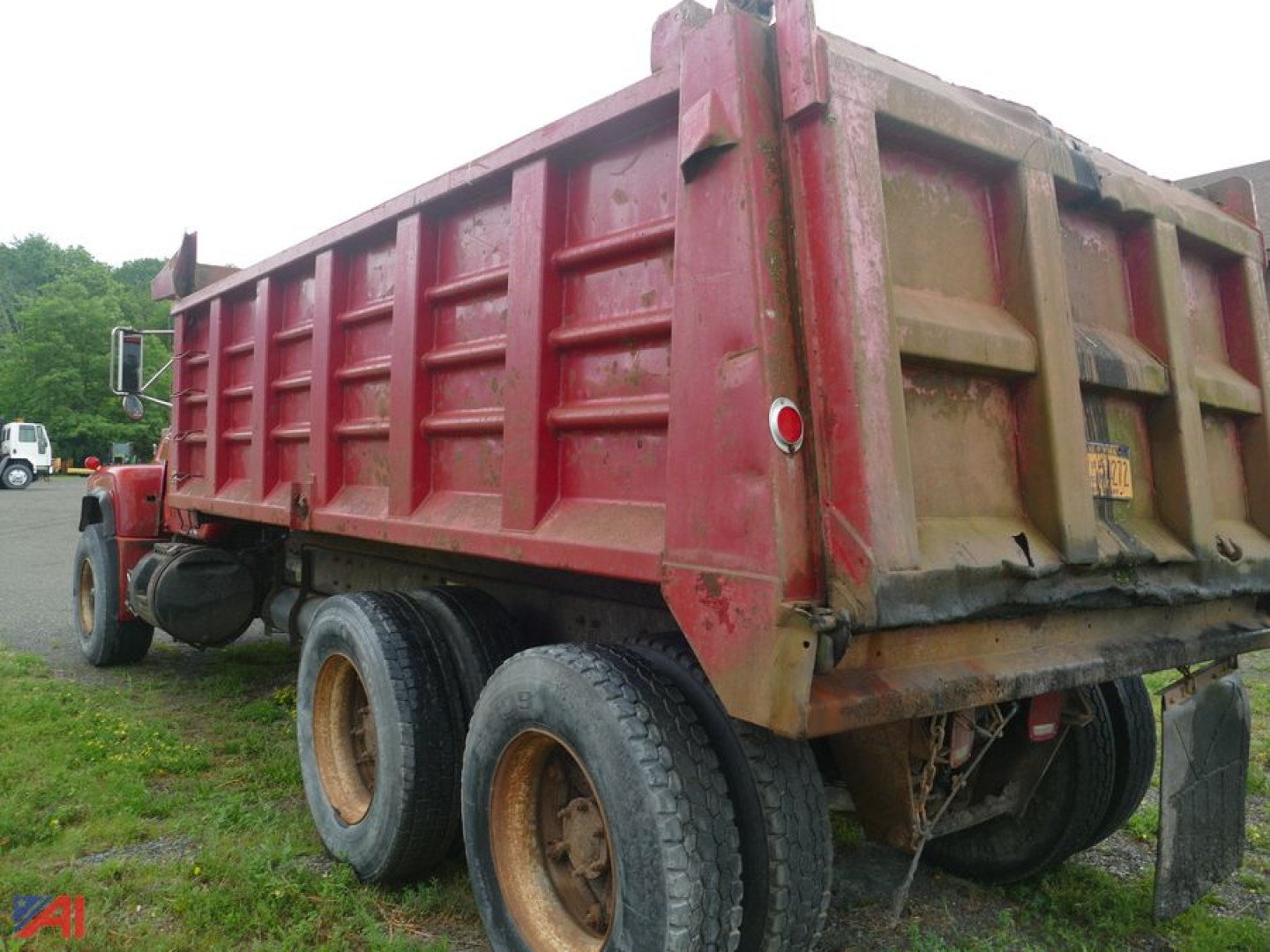 Dump truck bed of a red Mack RD690S dump truck viewed from rear-right showing dual rear axles and mud flaps.