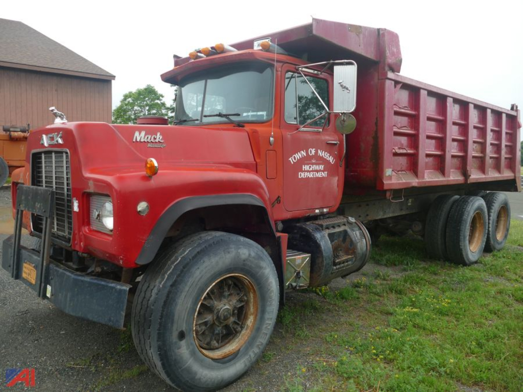 Mack RD690S dump truck in red with a large open-top dump bed and dual rear wheels, cab shows Mack logo and text on door.
