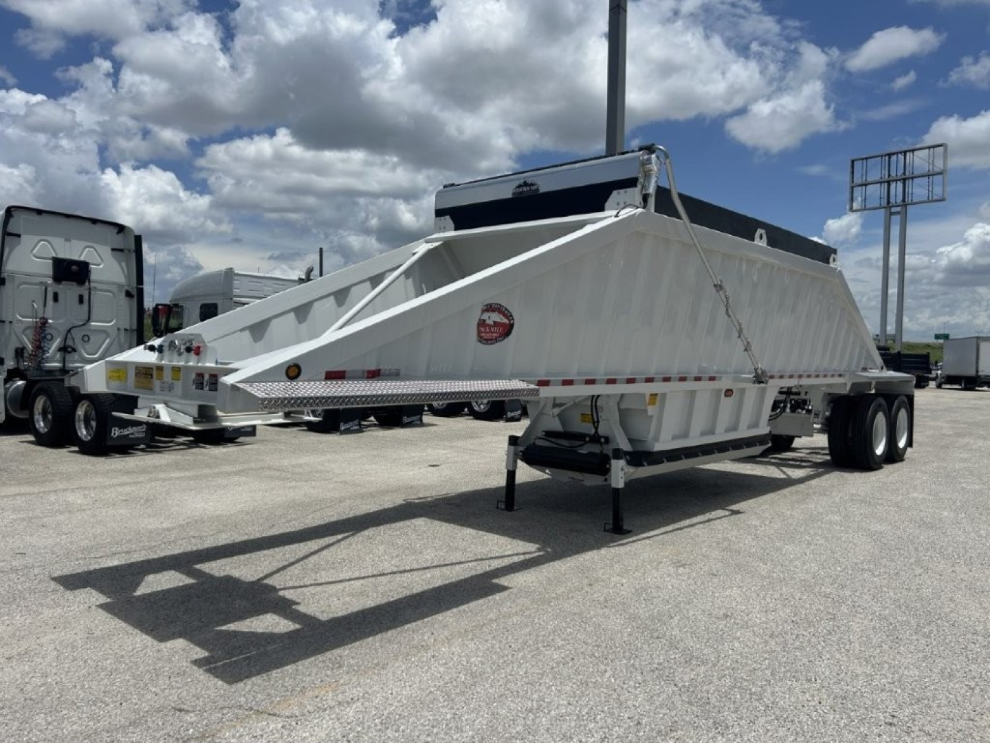 Trailer showing CTS BDT-40 spring dump trailer with white body and dual axles, side identification label, and hitch at front.
