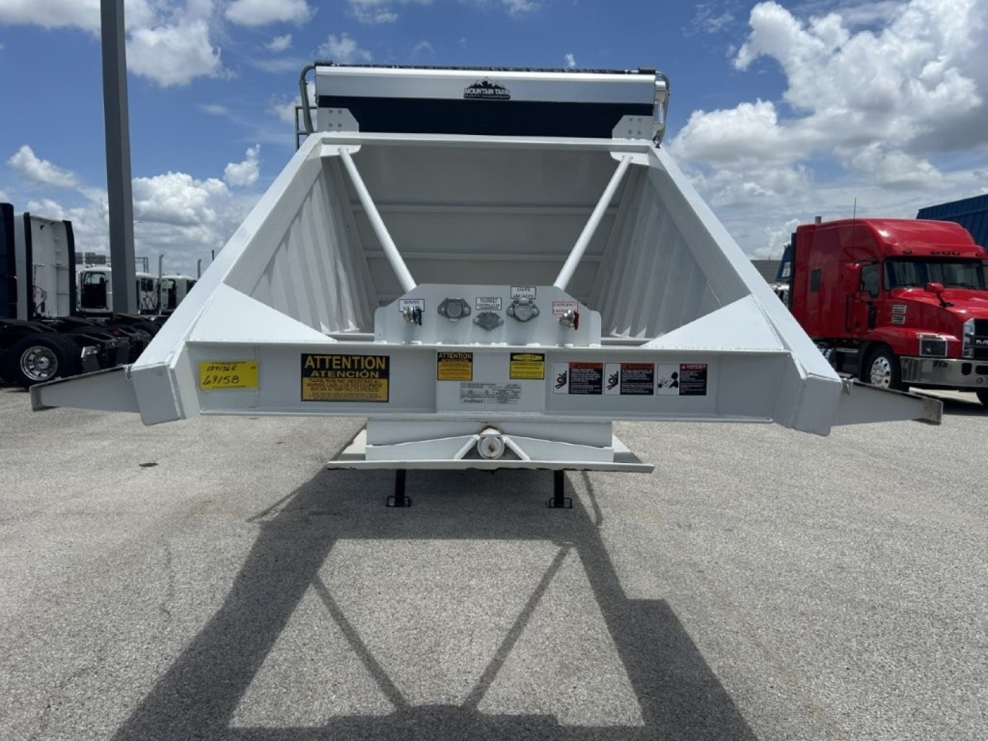 Trailer rear view showing CTS BDT-40 spring dump with warning labels and hitch, matching stock display in a truck lot.