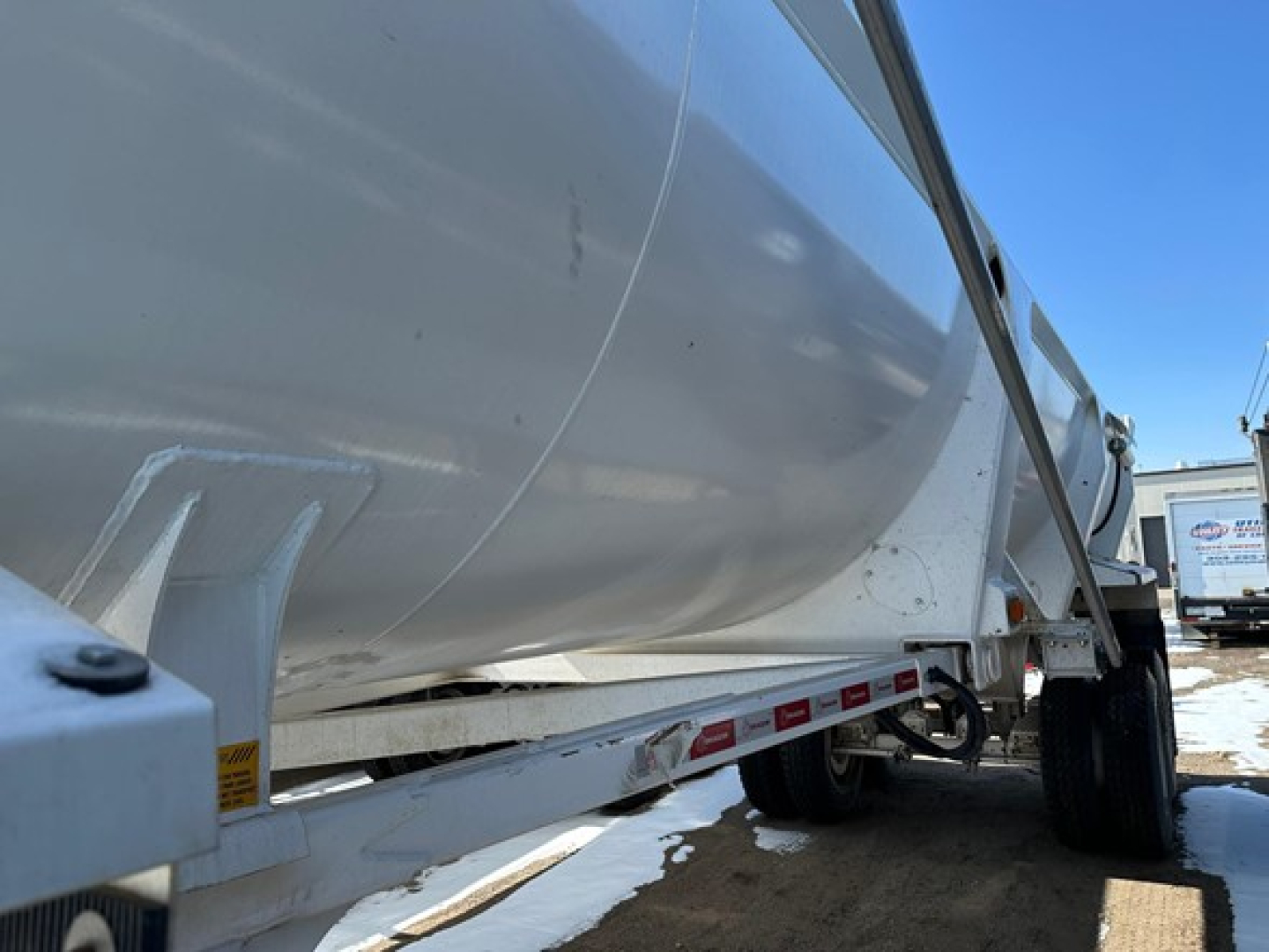 Dump trailer showing side view with white Ranco Ed26-34 model, wheel, and undercarriage.