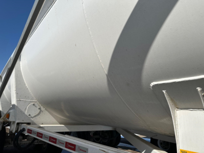 Dump trailer showing curved aluminum hull with support frame and fender, side view of Ranco ED26-34 equipment trailer.