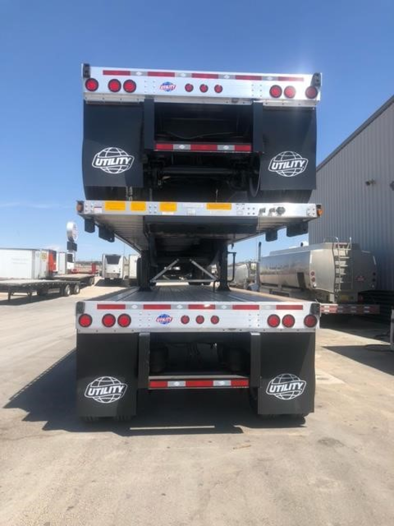 Trailer rear view showing Utility equipment with dual stacked flatbed trailers, branding 'Utility' on mudflaps, and red/white reflective tape.
