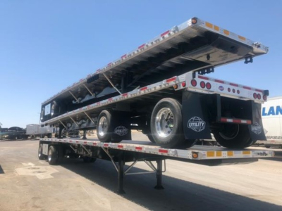 Utility 4000Ae  Meth trailer lying on its side with flatbed raised, dual rear axles, spare tire mounted, reflective tape, landing gear down.