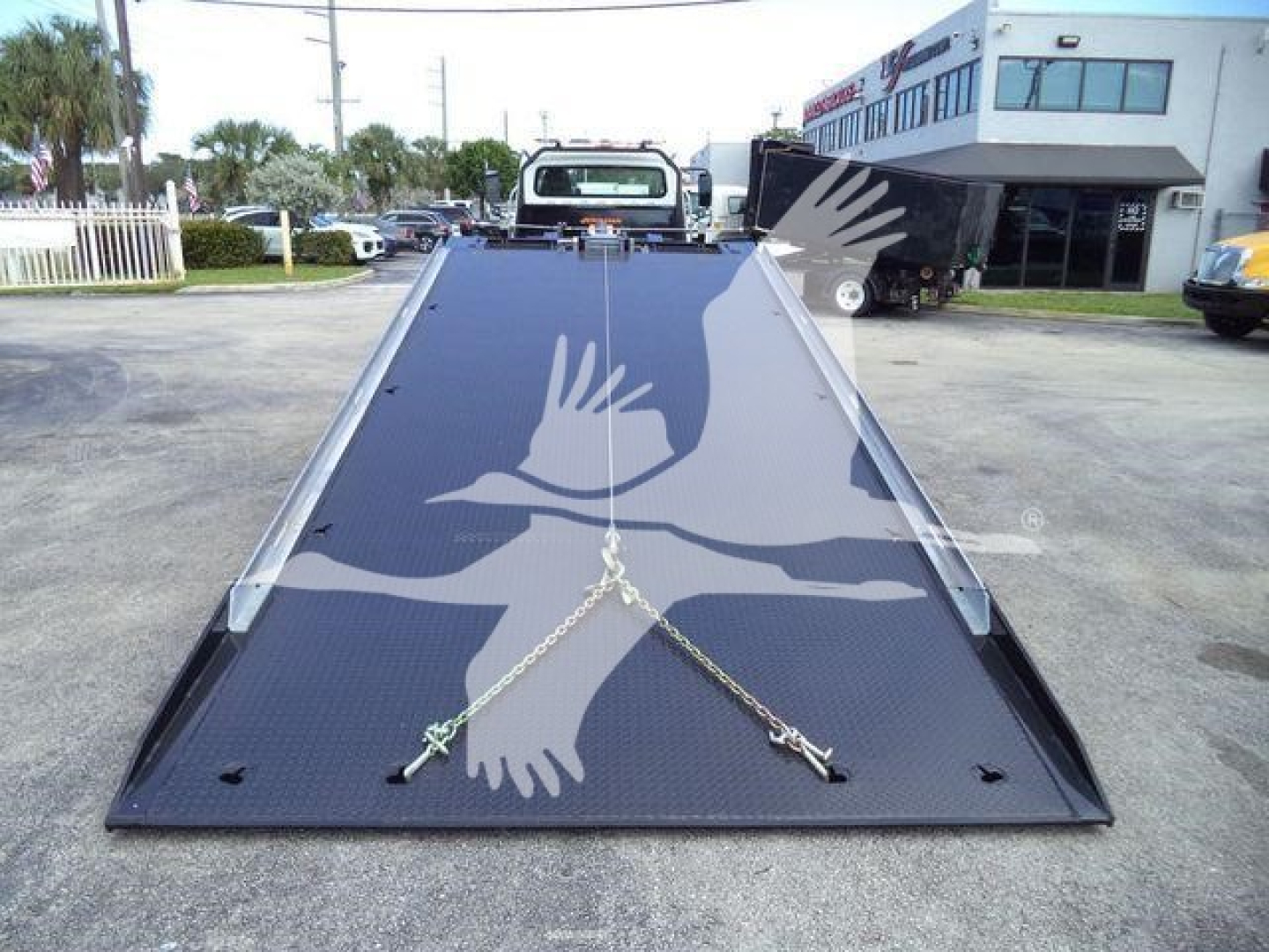 Flatbed truck ramp in lowered position with chains across the surface, 2019 Freightliner M2 106 equipment image.