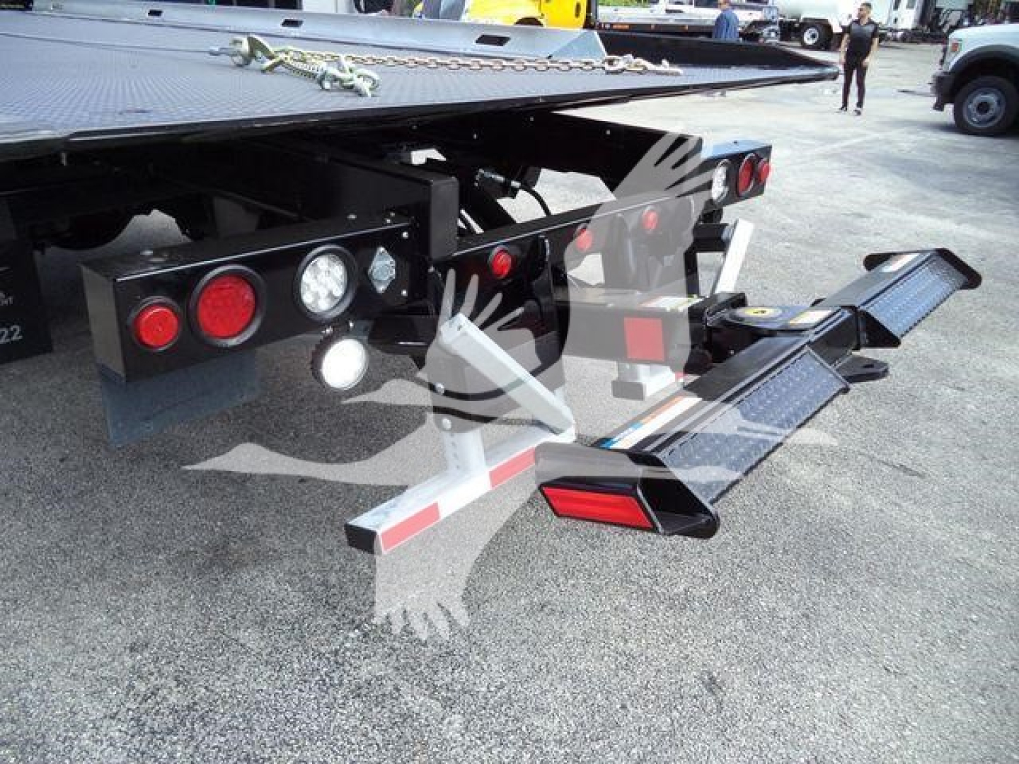 Freightliner M2 106 rollback platform rear showing taillights, hydraulic components, and folded loading ramps.