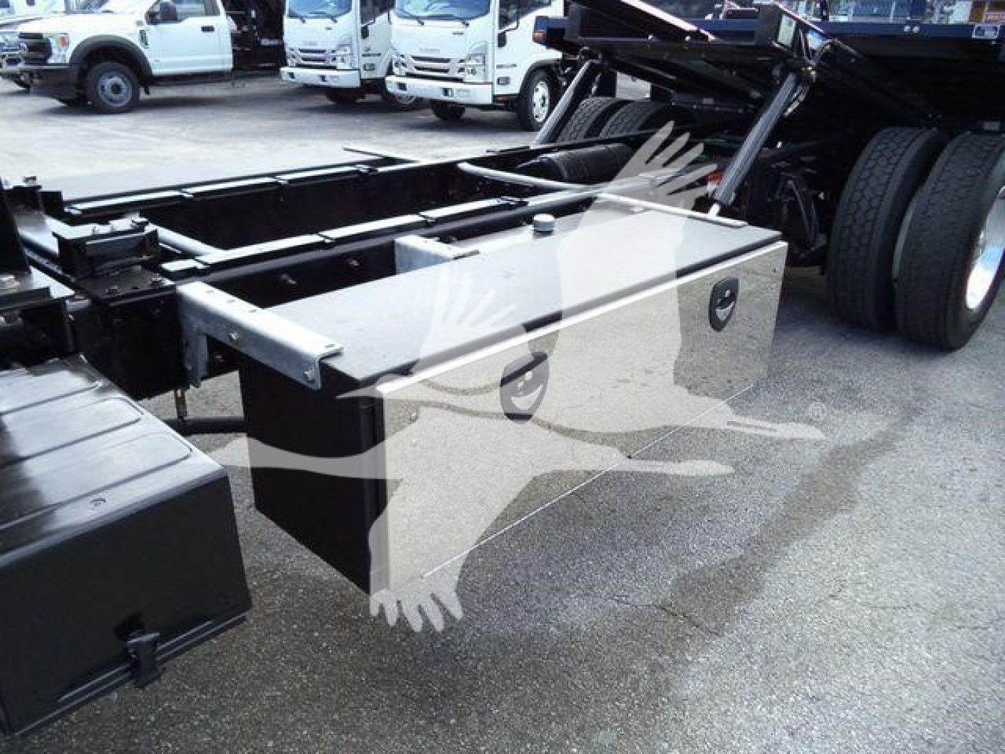 Truck chassis with large aluminum toolbox mounted beside rear axle of a 2019 Freightliner M2 106 rollback truck.