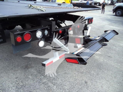 Freightliner M2 106 rollback platform rear showing taillights, hydraulic components, and folded loading ramps.