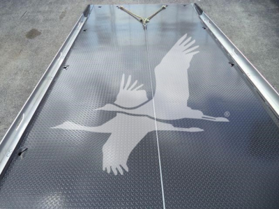 Truck bed surface with Diamond plate pattern and a faded graphic of flying birds on a Freightliner rollback truck bed.