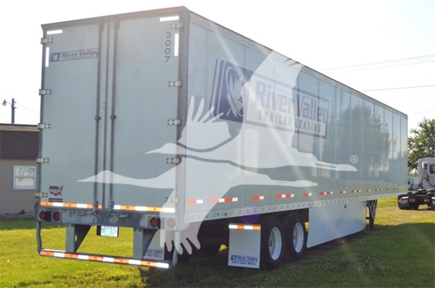 Trailer side showing River Bend Trailers logo and DuraPlate design, rear and side doors, dual rear axles with mud flaps, manufacturer markings.