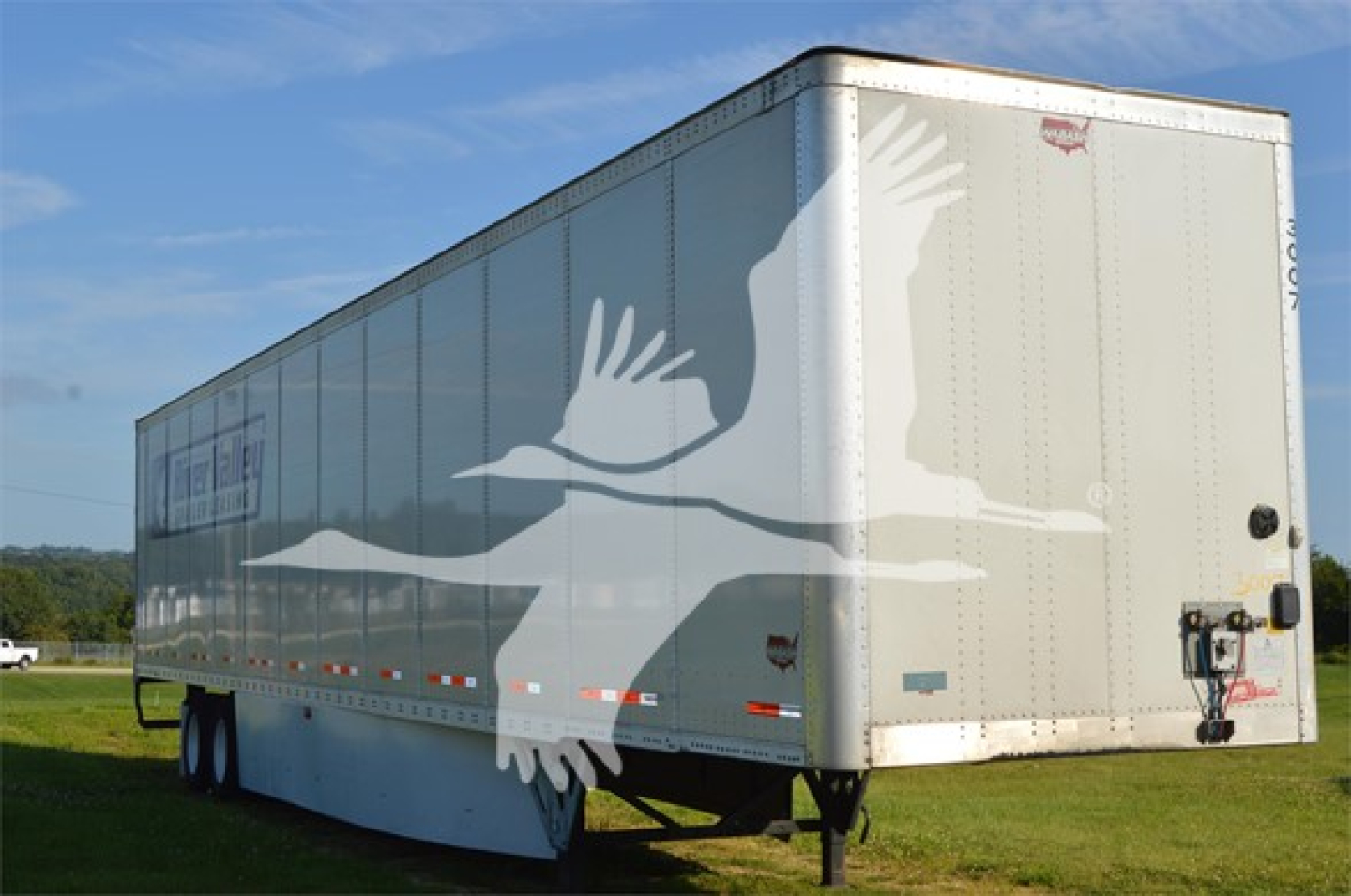 Wabash Duraplate trailer side and rear showing large white graphic of flying geese on the trailer with dual rear doors and wheels visible.