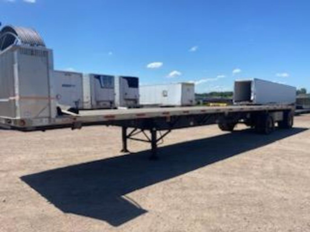 Flatbed trailer with multiple refrigerated units and a refrigeration unit at the front; shows landing gear and a clear blue sky.