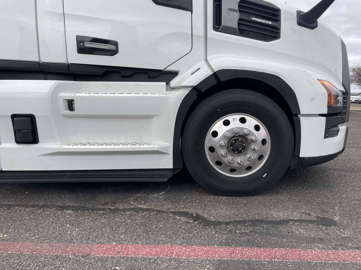 Front-right side of a white 2026 Mack PR64T conventional daycab showing front wheel and side step
