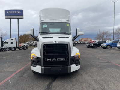 Front view of a white 2026 Mack PR64T conventional daycab truck in a dealership lot with black grille and amber turn signals.
