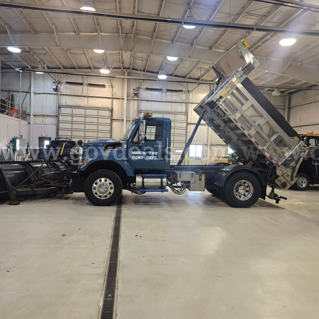 Truck in a warehouse with a raised dump bed on a blue International 7400 plow truck, workshop background, VIN 1HTWDAAR6DH187515 visible on listing.