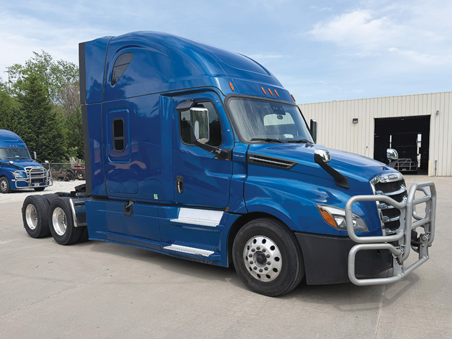 Blue Freightliner Cascadia126 sleeper cab tractor truck with front grille guard and chrome bumper, side fuel tanks, and triple-axle rear; no legible text visible on labels.