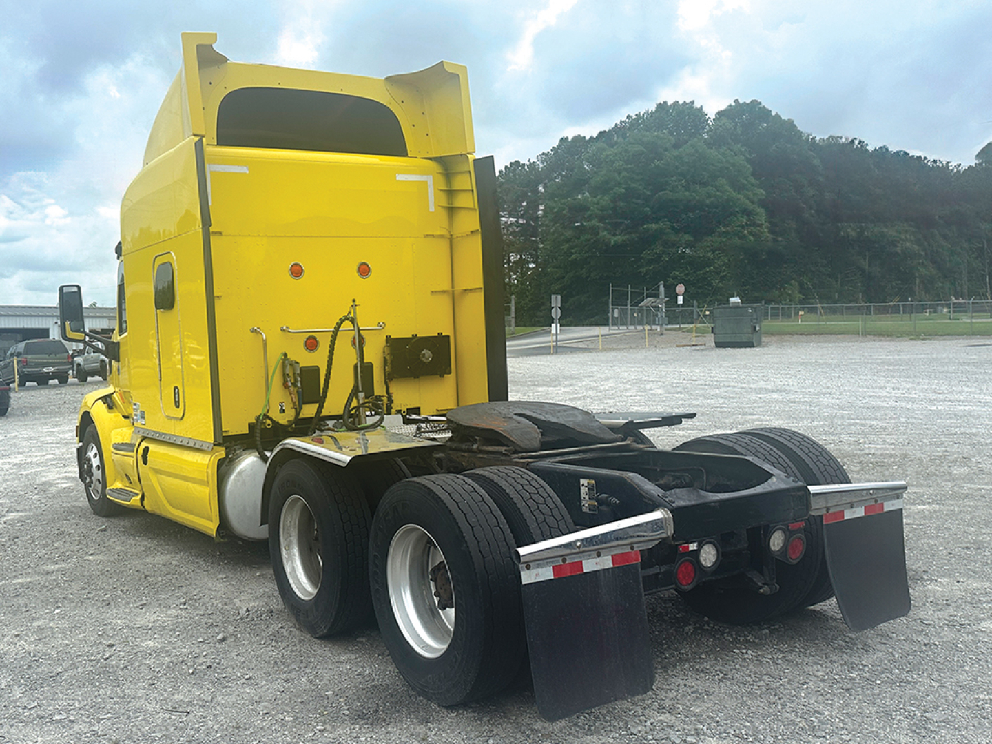 Yellow Peterbilt 579 UltraCab truck rear view showing fifth-wheel hitch and dual rear axles.