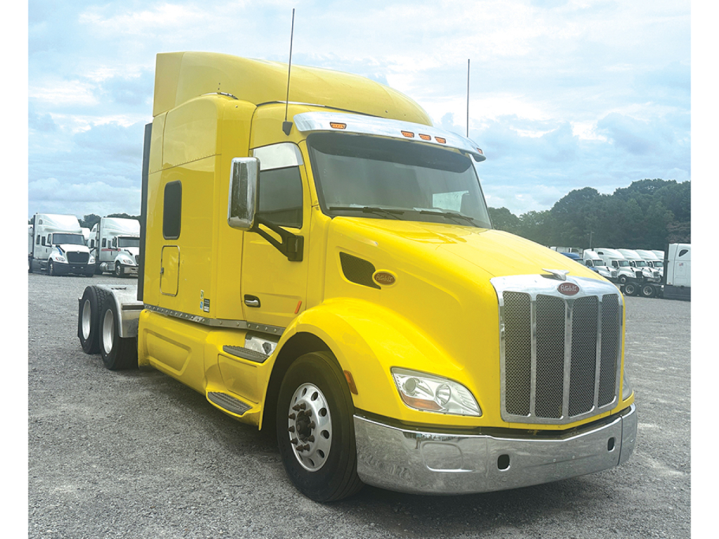 Peterbilt 579 UltraCab tractor in yellow, front-left view showing sleeper cab and chrome bumper.