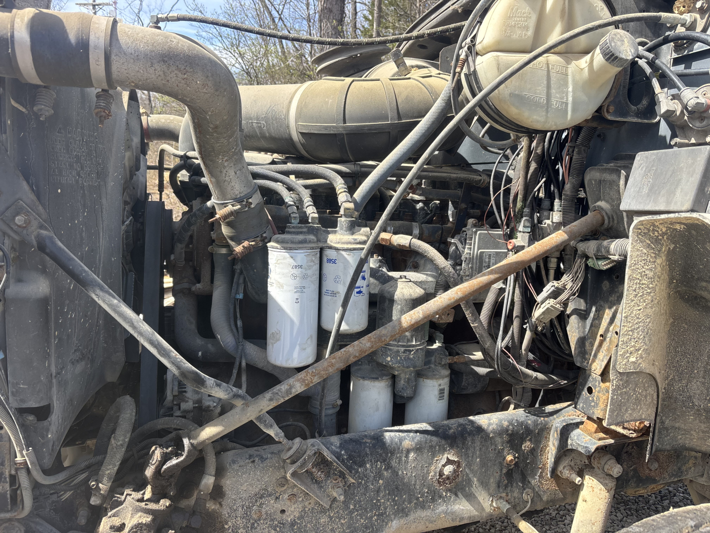 Engine bay of a used 2000 Mack CH613 day cab showing multiple filters and wiring harnesses with hoses and components.