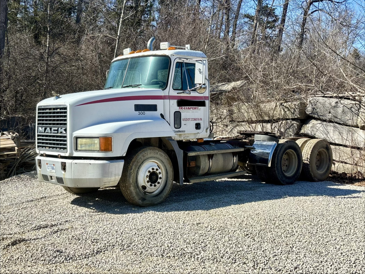 Mack CH613 day cab truck in-service showing front grille, white cab with red stripe, front wheel and sleeper window, chassis rear with dual axles and hitch.