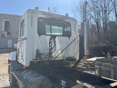 Truck cab of a 2000 Mack CH613 day cab tractor showing rear of cabin with aerodynamic vertical exhaust stack and fuel tanks.