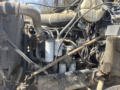 Engine bay of a used 2000 Mack CH613 day cab showing multiple filters and wiring harnesses with hoses and components.