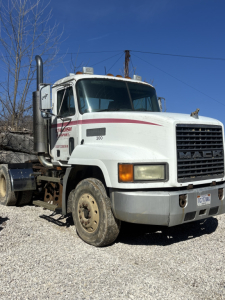 Mack CH613 day cab truck showing front grille with MAUK branding and large side exhaust stack, white paint with red stripe, visible headlight, bumper, and front tire.