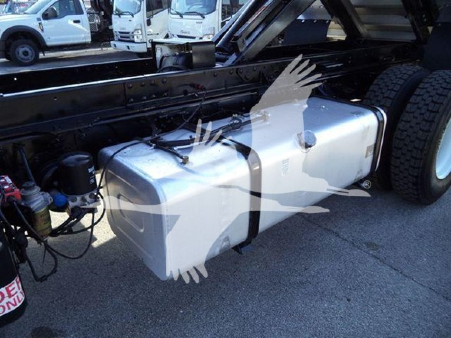 Isuzu truck chassis showing a large rectangular fuel tank mounted along the frame with hoses and components nearby.