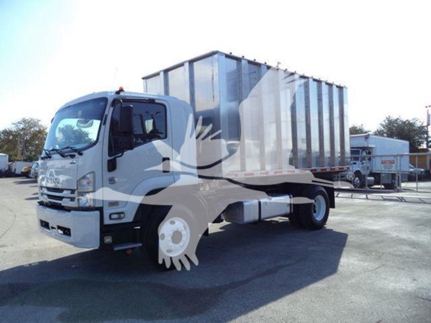 Isuzu medium-duty truck with a large rectangular box tanker/chipper body on a commercial lot. Cabin front view visible with Isuzu badge and side mirror.