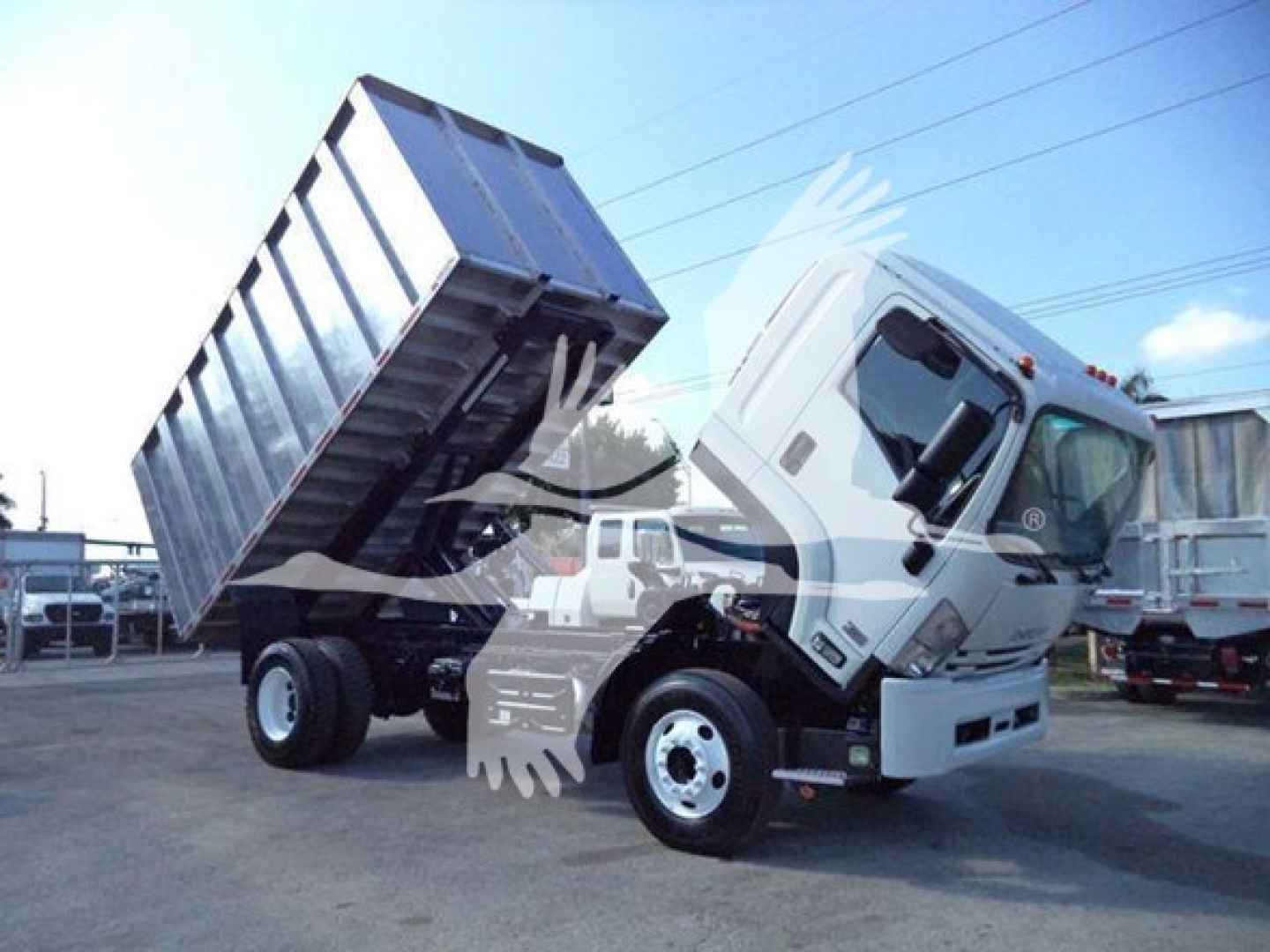 Isuzu FTR dump truck tilting its bed up to reveal the cargo area and chassis.