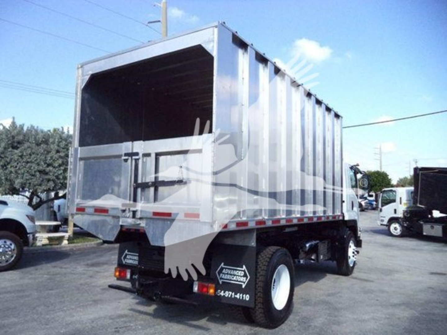 Isuzu FTR dump truck body rear/side view showing dump bed with metal panels and rear tailgate; visible tires and wheel wells