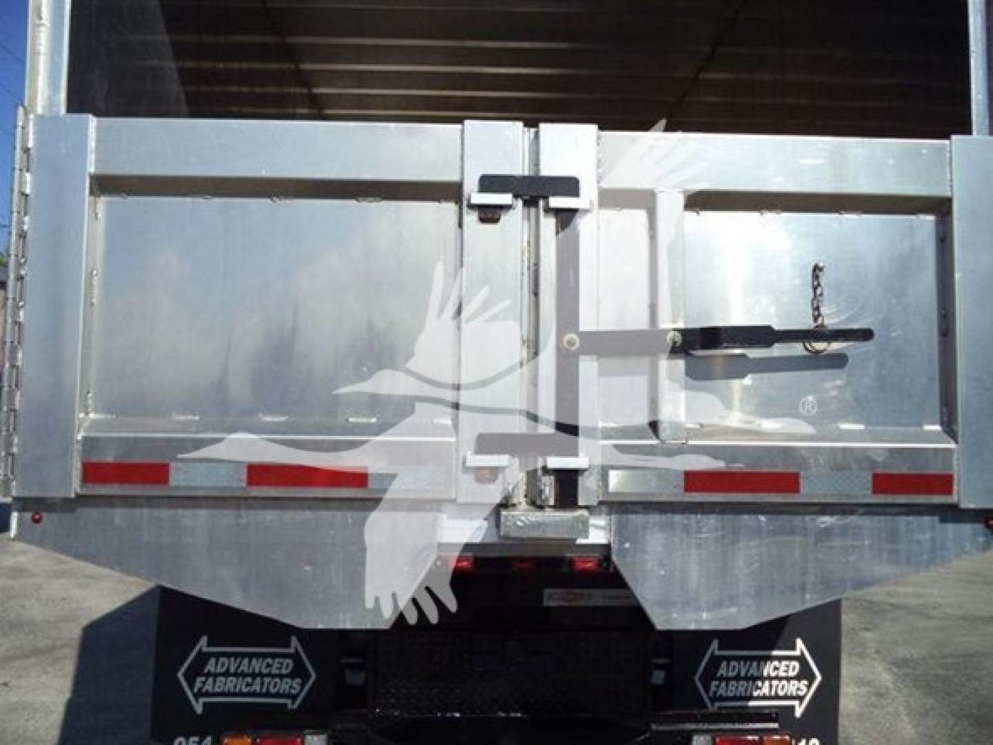 Isuzu FTR dump truck tailgate showing rear doors and latch with metal body and reflective red/white strips.