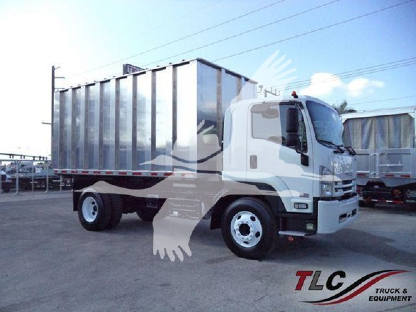 Isuzu FTR truck with a large dump bed, side view showing cab and cargo area, white cab with chrome grille, in-service equipment.