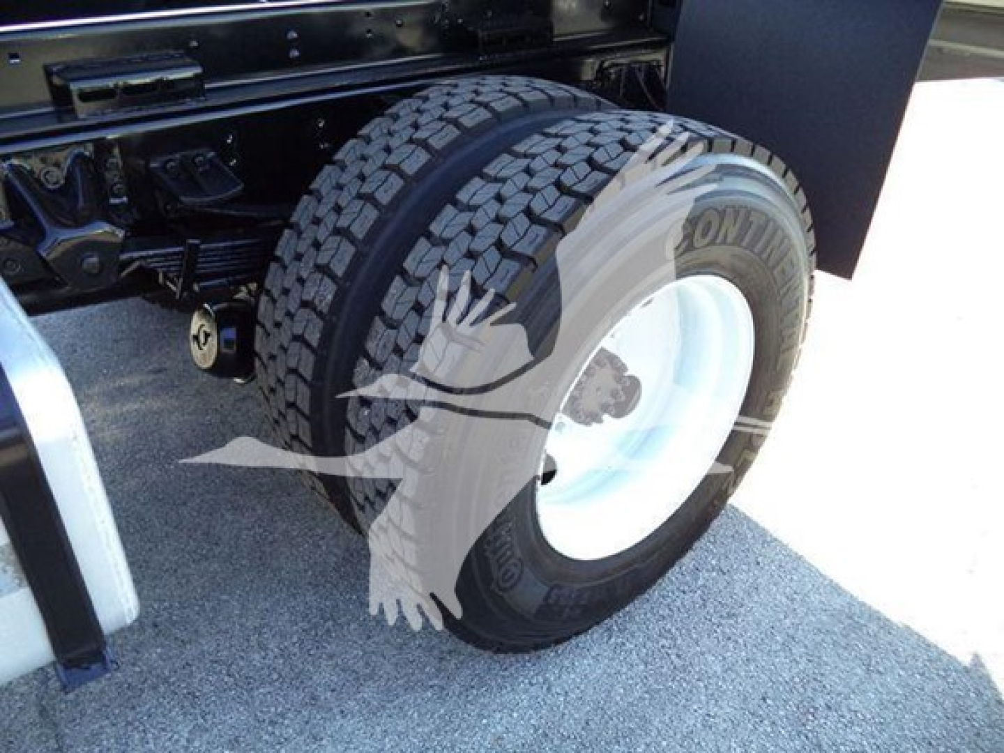 Isuzu FTR wheel and tire close-up showing front dual rear axle with Goodyear tire, white steel wheel, chassis frame in background.