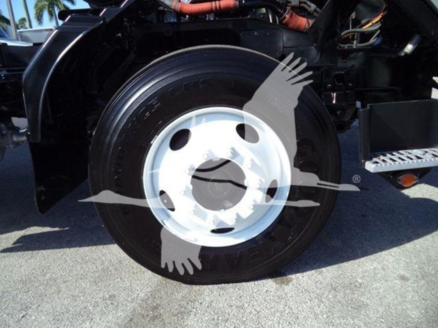 Isuzu FTR wheel and tire; visible text on tire reads 'TUBELESS' and 'SUPER SW…' (partial). Engine bay area with hoses and frame in background.