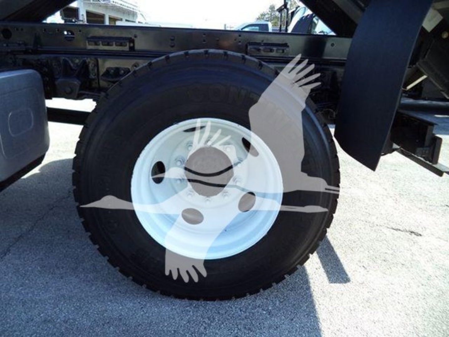 Isuzu FTR wheel and tire visible with white steel rim and black tire; part of rear chassis and fender visible